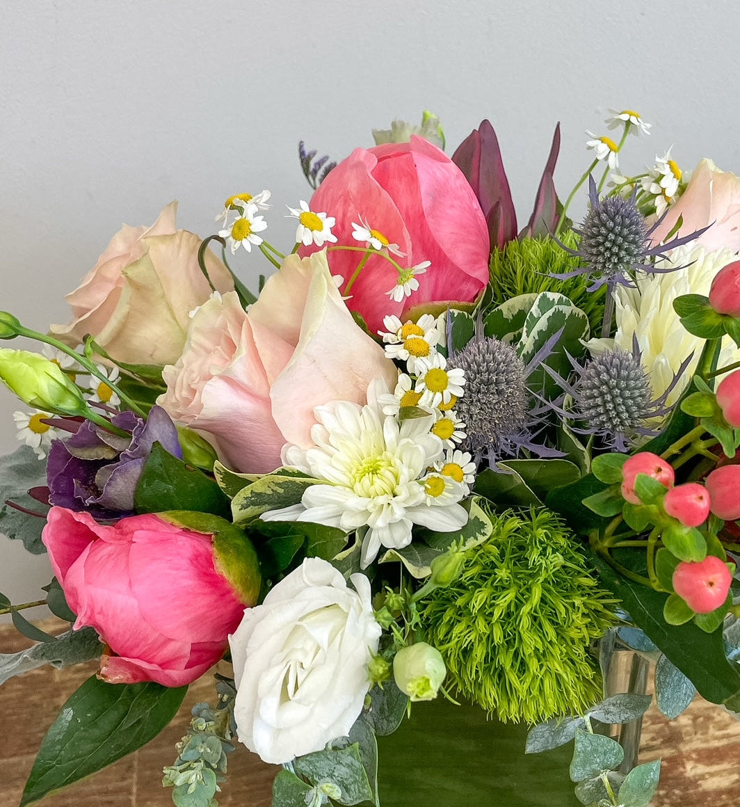 Bouquet of colorful flowers including roses and hydrangeas on a wooden surface.